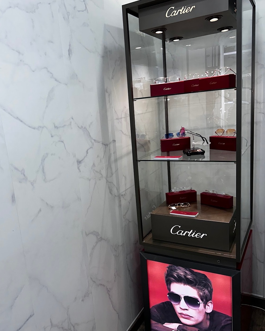 La vitrine Cartier de la boutique, montures présentées dans leurs écrins rouges sur fond de marbre blanc